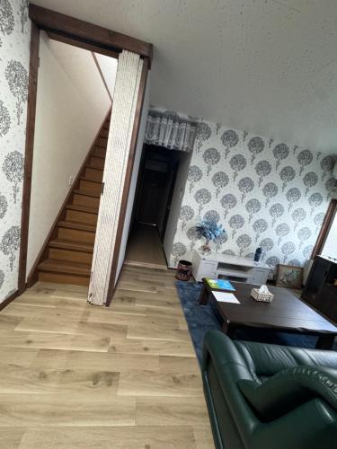 a living room with a staircase and a green couch at お宿花水木 in Nagasaki