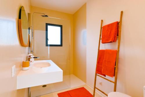 La salle de bains est pourvue d'un lavabo blanc et de serviettes orange. dans l'établissement villa vedra, à Pietrosella