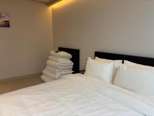 a bedroom with a bed with white sheets and pillows at Hotel Deokyeong in Wonju