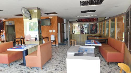 BelagulaHotel White Palace的餐厅设有橙色桌椅和时钟