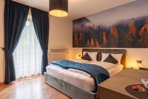 a bedroom with a bed with a large painting on the wall at Kyrr Smart Mountain Retreat in Moena