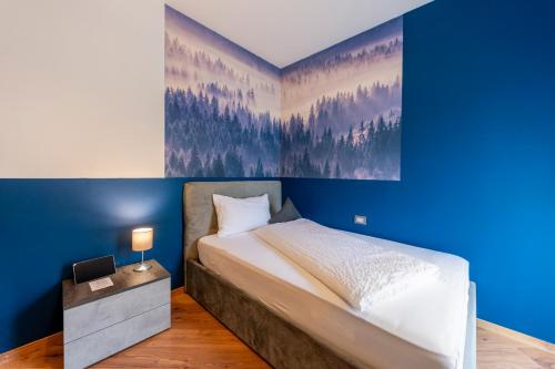 a bedroom with a blue accent wall and a bed at Kyrr Smart Mountain Retreat in Moena