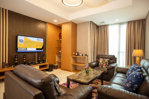 a living room with leather furniture and a flat screen tv at Nagoya Hill Hotel Batam in Nagoya