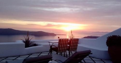 a view of a sunset from a balcony with a table and chairs at Vallais Villa in Imerovigli