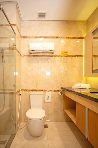 a bathroom with a toilet and a glass shower at Nagoya Hill Hotel Batam in Nagoya