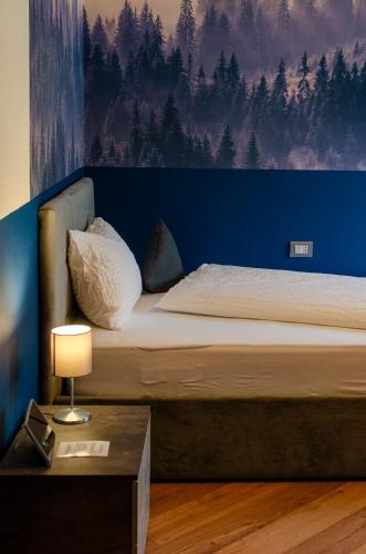a bedroom with a bed with a blue wall at Kyrr Smart Mountain Retreat in Moena