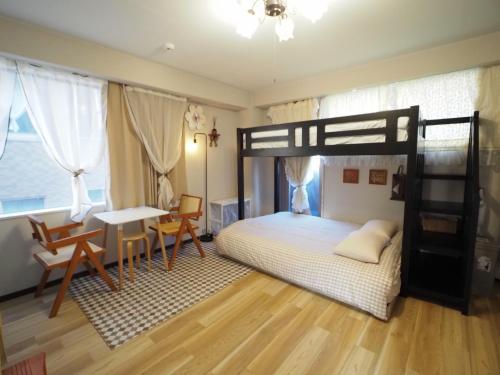 ein Schlafzimmer mit einem Etagenbett, einem Schreibtisch und einem Tisch in der Unterkunft UENO 704 jellynehouse in Tokio
