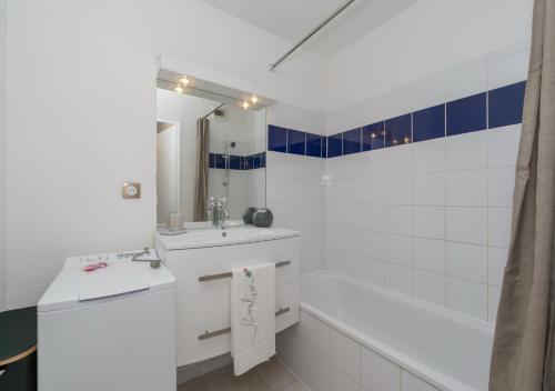 a white bathroom with a tub and a sink and a bath tub at Lumaïa - Vue cité, terrasse & Piscine in Carcassonne
