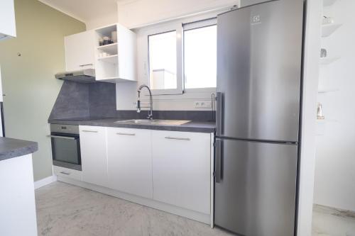 une cuisine avec des armoires blanches et un réfrigérateur en acier inoxydable dans l'établissement Stella Mare-Vue mer-clim-terrasse, à Menton