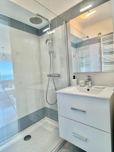 une salle de bain avec un lavabo blanc et une douche dans l'établissement Stella Mare-Vue mer-clim-terrasse, à Menton