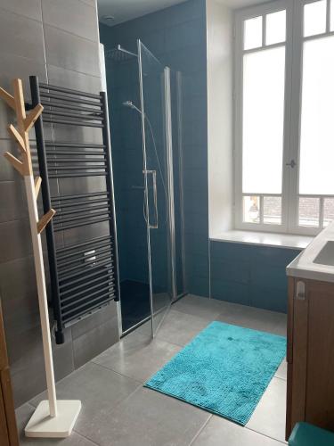 La salle de bains est pourvue d'une douche avec un mur bleu. dans l'établissement Superbe duplex T4, au coeur de Batz, tout à pied !, à Batz-sur-Mer