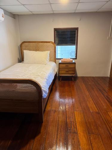 a bedroom with a bed and a wooden floor at Traditional Thai House Chaloklum in Chaloklum