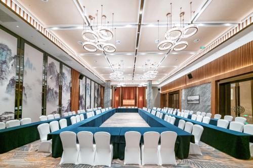 a conference room with a long table and white chairs at Shangrao International Hotel in Shangrao