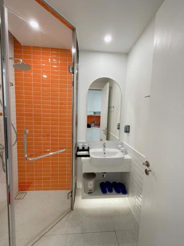 an orange and white bathroom with a sink and a shower at Hillside apartment sunset town city in Phu Quoc