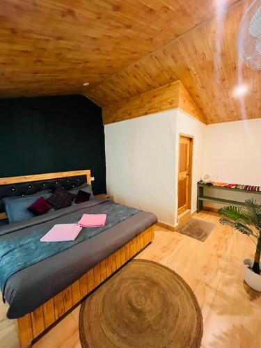 a bedroom with a large bed with a wooden ceiling at The Dreamcatcher room’s & cafe in Kasol