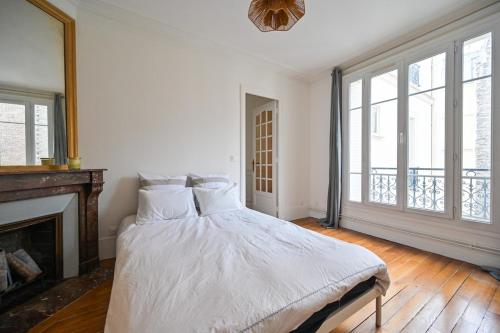 une chambre blanche avec un lit et une cheminée dans l'établissement Apartment Suite Parties 17, à Paris