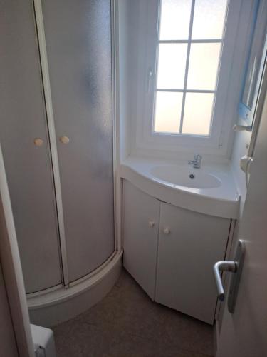 une salle de bain blanche avec un lavabo et une fenêtre dans l'établissement Mobil home 6 personnes, à Saint-Gilles-Croix-de-Vie