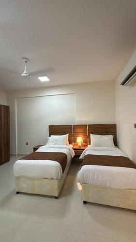 two beds in a large room with two lamps at Middle East Building in Salalah