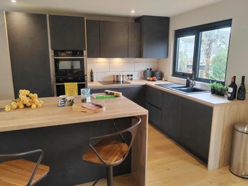 a kitchen with black cabinets and a wooden counter top at Modern open plan house, sea views and hot tub in Falmouth