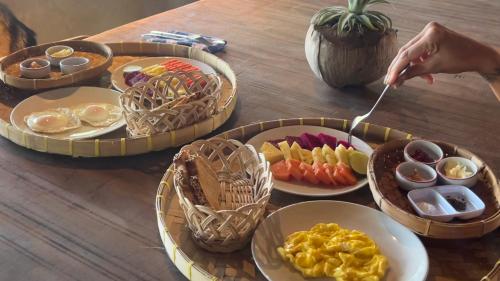 un tavolo con diversi piatti di cibo e una persona che tiene in mano un cucchiaio di Gili Dua Resort a Sekongkang