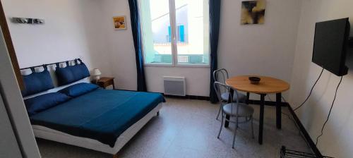 a bedroom with a bed and a table and a window at GitesLuberon 1 studio in Charleval