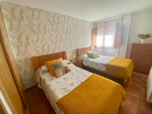 two beds in a small room with yellow sheets at El palacio de Juana in Tordesillas
