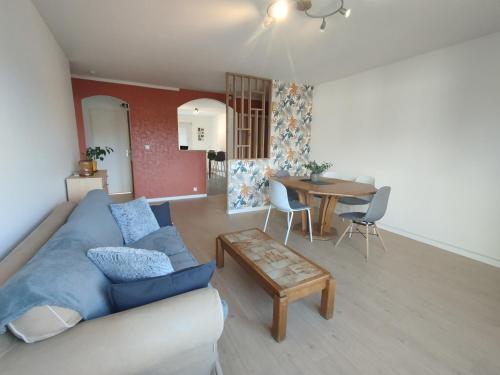 un salon avec un canapé bleu et une table dans l'établissement F3 rénové, à Arbent