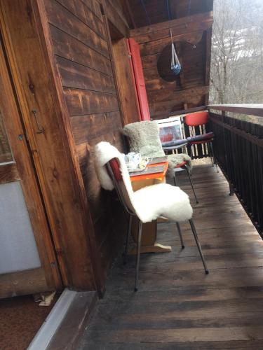 a porch with two chairs and a table on a deck at Chalet Chinegga in Stalden