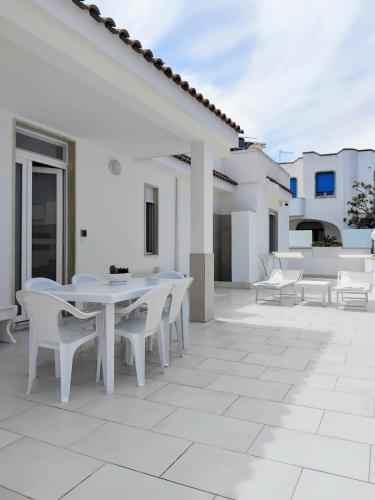 a white patio with white tables and white chairs at Villa Incanto Pina - Torre Canne in Torre Canne