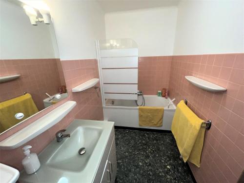 La salle de bains rose est pourvue d'une baignoire, d'un lavabo et d'une baignoire. dans l'établissement Superbe appartement duplex en cœur de station, à La Celle-sous-Gouzon