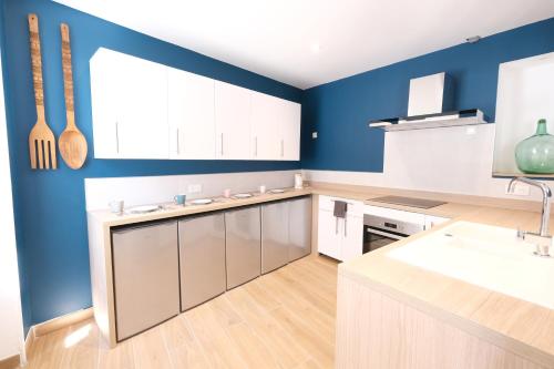 une cuisine avec des murs bleus et des armoires blanches dans l'établissement La maison de Lili, à Sisteron