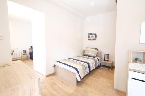 une chambre avec un lit dans une pièce blanche dans l'établissement La maison de Lili, à Sisteron