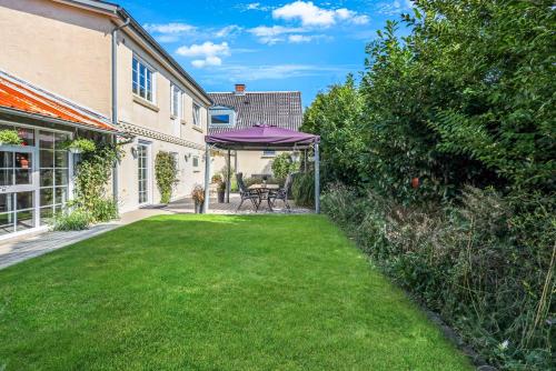 a lawn with a purple umbrella in a yard at Like Home Holiday House 9 B in Varde