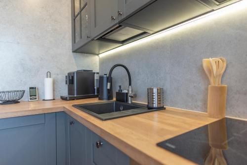 a kitchen counter with a sink and a microwave at Apartament Ustka Holiday z sauną i ogrodem in Ustka