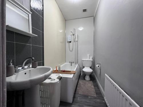 Un baño blanco con lavabo e inodoro. en Cheerful 5 Bedroom House Close to Central West End and Parking, en Glasgow