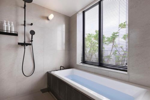 a bathroom with a bath tub and a window at Southwest Grand Hotel in Naha