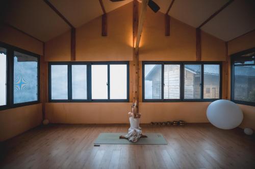 a woman doing yoga in a room with windows at The Well House in Jiayi