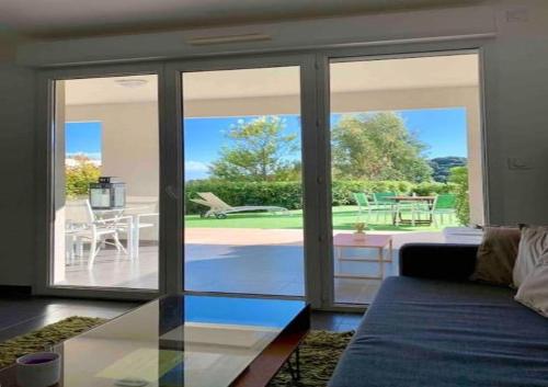 - un salon avec des portes coulissantes en verre donnant sur une terrasse dans l'établissement Domaine Blue Park 2 pièces, piscine, jardin privé, climatisation, parking et vue, à Antibes