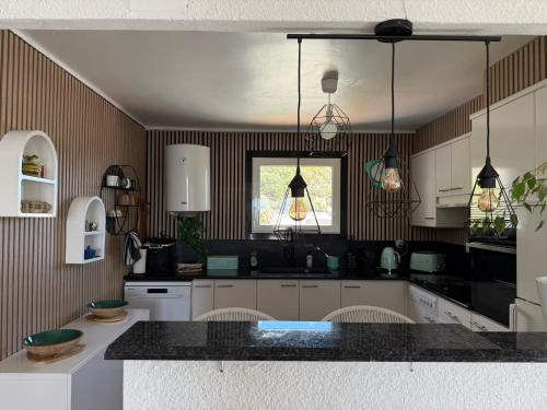 Una cocina con gabinetes blancos y una encimera negra. en Villa à Canyelles, piscine et SPA à bulles privés , vue panoramique, en Roses