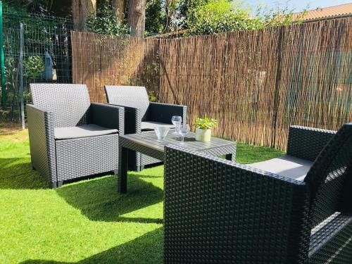 a patio with three chairs and a table on grass at Studio in Boucau