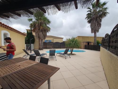 un homme debout devant un patio avec une piscine dans l'établissement Villa de l Ode, à Mirepeisset