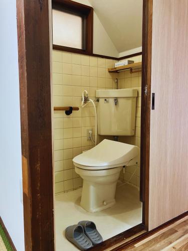 a bathroom with a toilet and a pair of slippers at 二本木の宿 in Kumamoto