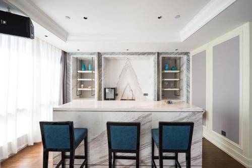a large kitchen with a bar with four chairs at Shangrao International Hotel in Shangrao