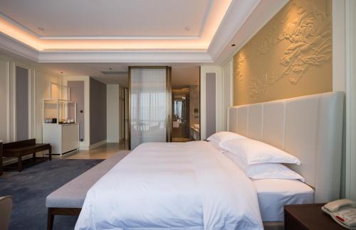 a bedroom with a large bed with white sheets and pillows at Shangrao International Hotel in Shangrao