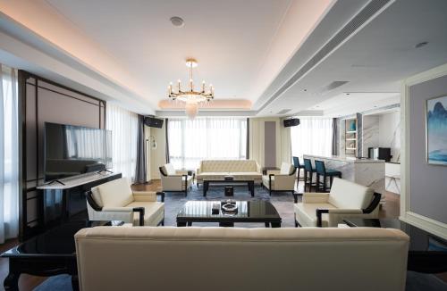a living room with a couch and chairs and a television at Shangrao International Hotel in Shangrao