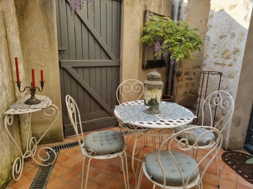 d'une terrasse avec une table, des chaises et un portail. dans l'établissement Charmante maison ancienne avec cour, à Aleçon