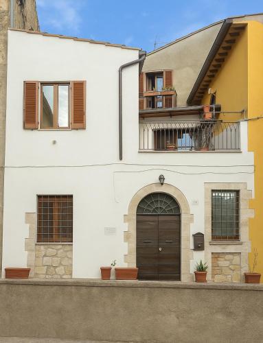 a white house with a brown door and a balcony at La Comoedia in Amelia