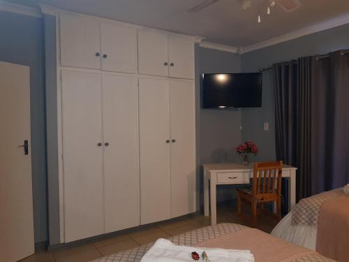 a bedroom with white cabinets and a desk and a television at Graceland Guesthouse in Potchefstroom