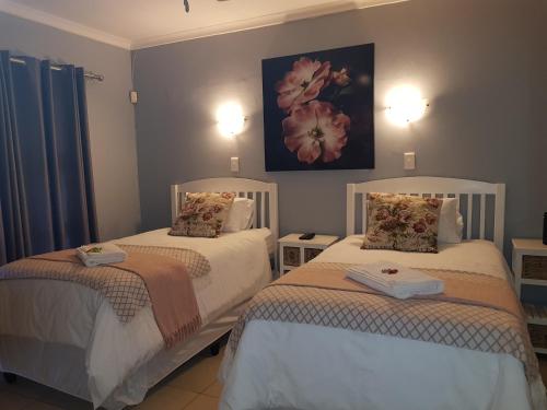 a bedroom with two beds and a painting on the wall at Graceland Guesthouse in Potchefstroom