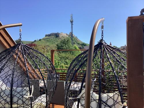a bird cage on a balcony with a mountain in the background at Relax Apartman in Sümeg